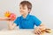 Young cute boy at the table chooses between fastfood and healthy diet on white background