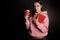 A young cute brunette in a pink hoodie, holding a book and coffee in her hands.