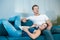 Young cute couple beautiful brunette woman lying on handsome man`s leg while watching movie on the sofa and eating