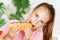 Young cute european girl in t-shirt is eating unhealthy food like hot dog and chips