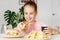 Young cute european girl in t-shirt is eating unhealthy food like hot dog and chips