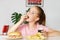 Young cute european girl in t-shirt is eating unhealthy food like hot dog and chips