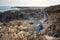 Young cute girl sits in bliss on the rocks amidst the raging blue sea