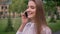 Young cute girl is talking on phone in park in summer, emotional concept, communication concept