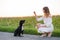 Young cute girl training a dog Russian Spaniel. Black doggie sits to her owner. sunset in nature