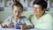 Young cute granddaughter teaching grandmother how to use smartphone at home