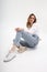 Young cute pensive caucasian girl posing in white shirt, blue jeans at studio