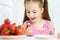 Young cute smiling european little girl is eating ripe jucy strawberry with sour cream and holding white plate of many