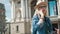 Young cute tourist is talking on the phone outside, wearing hat, glasses