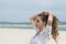 Young cute woman on the beach fixing her ponytail