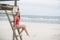 Young cute woman in red monokini on a wooden lifeguard tower