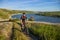 Young cyclist riding mountain bike uphill along a country road above river.