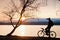 Young cyclist silhouette on blue sky and sunset background on beach. End of season at lake.