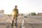 Young cyclist stands in a cap and sportswear stands with a white highway bike