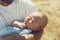 Young dad holds a newborn baby while walking in nature. happy father is wearing shorts and a t-shirt. International Father`s Day