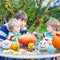 Young dad and two little sons making jack-o-lantern for hallowee