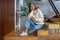 Young dark-haired pretty woman in jeans and white sweater at home