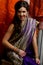 The young dark-haired woman in the rich Indian saris and colorful bracelets smiling on a background of silk screen