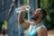 Young dark-skinned athlete pouring some refreshing water on himself after workout