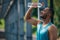 Young dark-skinned athlete pouring some refreshing water on himself after workout