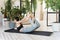 Young darkhair woman practicing yoga in the morning at her home near plants. The woman is engaged in self-determination