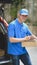 Young delivery man checking the products to customer while standing right next to his car and smiling to the camera