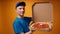 Young deliveryman in blue uniform opens a box of fresh pizza against yellow background