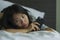 Young depressed Asian Chinese woman on bed sad and worried checking online news about covid-19 virus outbreak on mobile phone