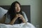 Young depressed Asian Korean woman on bed sad and worried checking online news about covid-19 virus outbreak on mobile phone