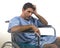 Young depressed and frustrated injured man in hospital patient gown desperate and upset at wheelchair after suffering accident or