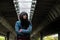 Young depressed homeless girl or woman standing alone under the bridge on the street on the cold weather feeling anxious abandoned