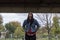 Young depressed homeless girl or woman standing alone under the bridge on the street on the cold weather feeling anxious abandoned