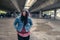 Young depressed homeless girl or woman standing alone under the bridge on the street on the cold weather feeling anxious abandoned