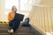 Young depressed lonely female college student sitting on stairs at her school, writing on her laptop.