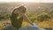 Young depressed woman in black short summer dress sitting on a mountain hill thinking outdoors at sunset. Lonely female contemplat