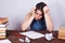 Young desperate student woman sitting at the table with empty pa