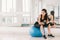 Young and determined Asian girl on fitness ball at gym with copy space, sport and healthy lifestyle concept