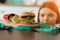 Young dieting woman sitting in front of plate with delicious junky food, looking at forbidden food with unhappy