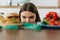 Young dieting woman sitting in front of plate with delicious junky food, looking at forbidden food with unhappy and hungry