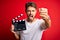 Young director man with beard making movie using clapboard over isolated red background annoyed and frustrated shouting with