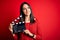 Young director woman with blue eyes making movie holding clapboard over red background with a happy face standing and smiling with