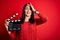 Young director woman with blue eyes making movie holding clapboard over red background stressed with hand on head, shocked with