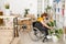 Young disable woman in casualwear sitting in wheelchair and watering green plant