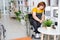 Young disable woman in wheelchair watering domestic fern plant in flowerpot