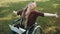 Young disabled caucasian woman in the wheelchair with laptop enjoying the autumn day in the park with music from