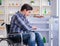 Young disabled injured man opening the fridge door