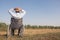 Young disabled man with field background.He is wearing a hat and sitting on wheelchair.He is looking into sky.