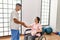 Young disabled woman and physiotherapist smiling happy shaking hands at the clinic