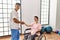 Young disabled woman and physiotherapist smiling happy shaking hands at the clinic