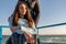 Young disabled woman in wheelchair with her mother walking near the sea on the ramp for people with disabilities. Family